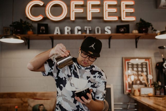 barista pouring milk into a coffee mug