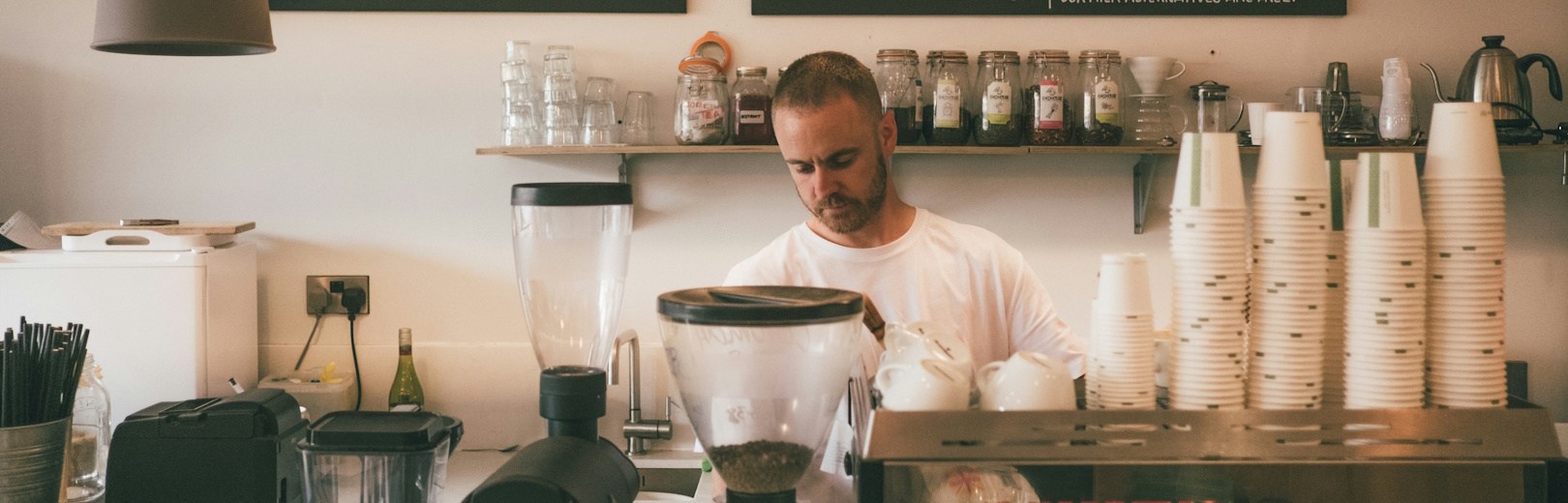 A barista behind an espresso machine in a coffee shop.