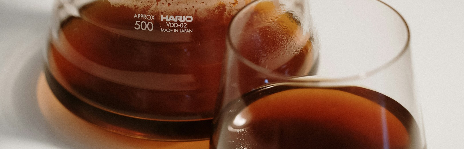 Filter coffee in a carafe next to a glass of brewed coffee.