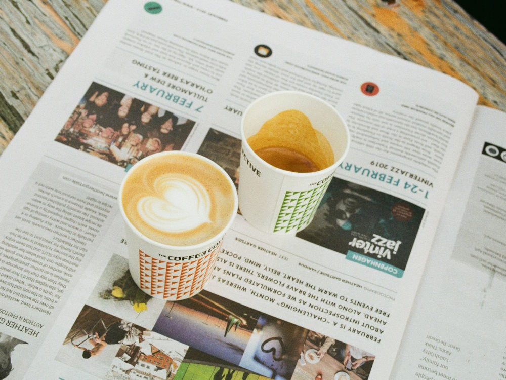 An espresso and a cappuccino in takeaway coffee cups.