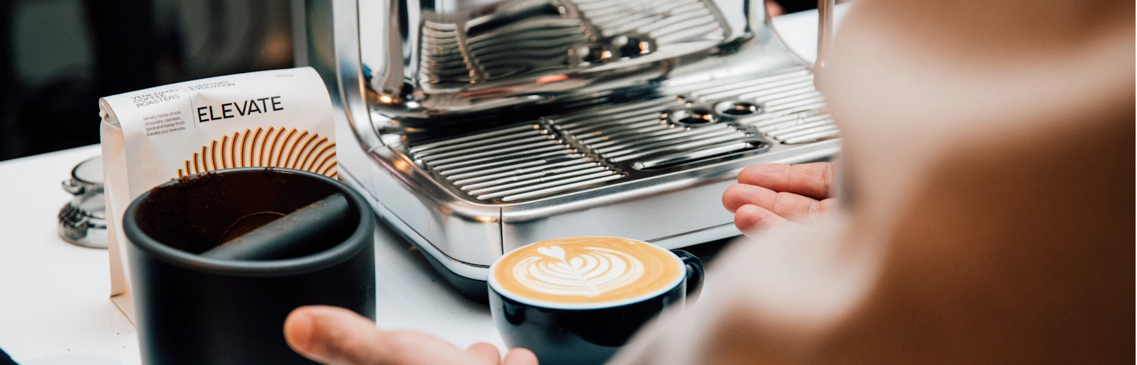 A Breville espresso machine next to a milk-based drink.