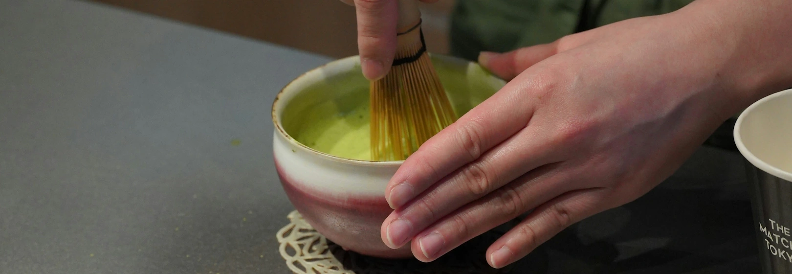 A barista whisks matcha in a bowl.