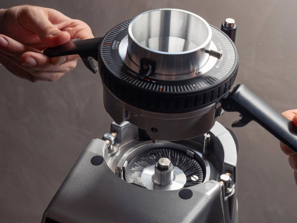A barista removes burrs from a Fiorenzato grinder.