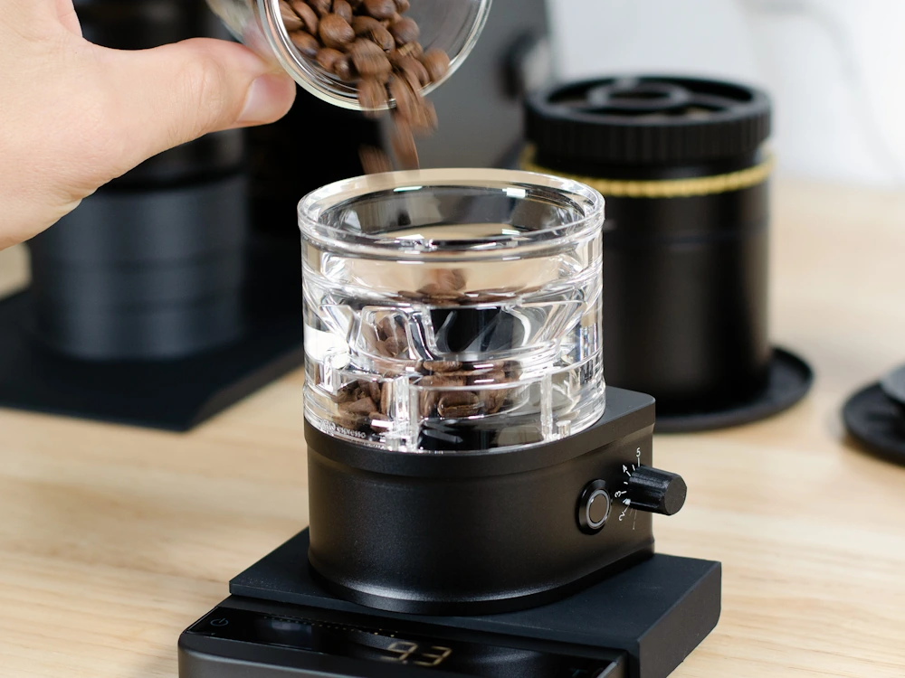 A person pours coffee beans into an Aro Slow Feeder Pro.